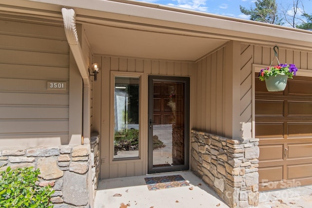 doorway to property with stone siding and a garage