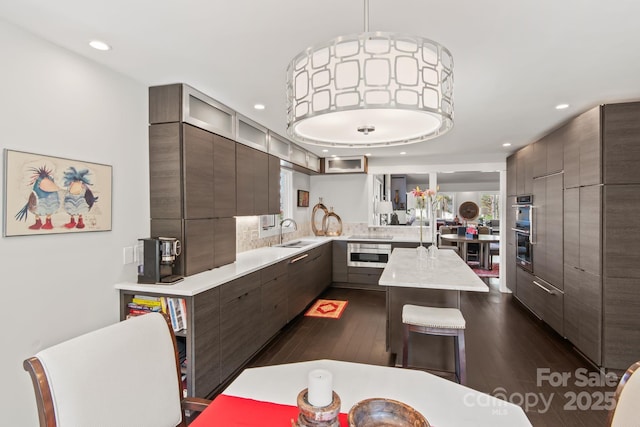 kitchen with light countertops, modern cabinets, recessed lighting, dark wood finished floors, and a sink