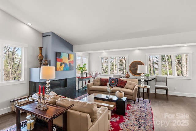 living area with baseboards, lofted ceiling, wood finished floors, and a healthy amount of sunlight