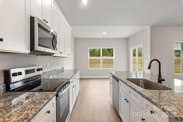 7015 Jerimoth Dr, Charlotte, NC 28215 - kitchen with stainless steel appliances, a sink, light wood finished floors, white cabinetry, and baseboards