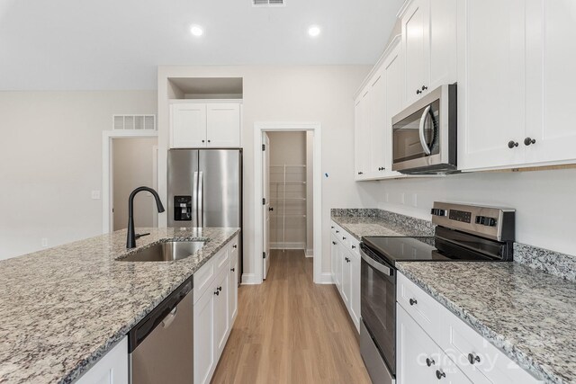 7015 Jerimoth Dr, Charlotte, NC 28215 - kitchen featuring stainless steel appliances, a sink, light wood-style flooring, white cabinetry, and light stone counters
