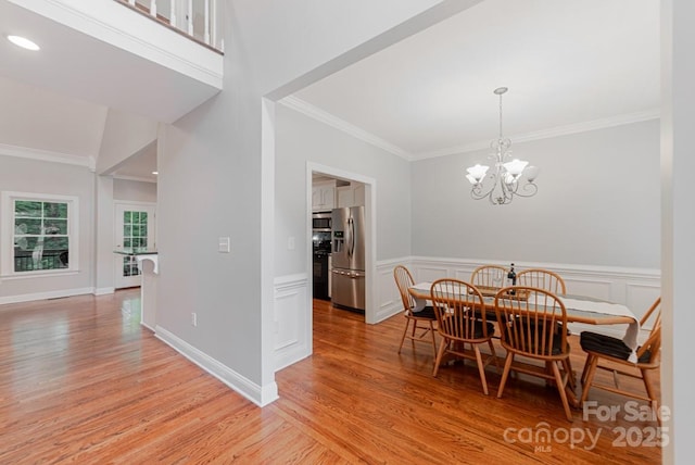 6414 Winding Creek Ln, Denver, NC 28037 - dining area with light wood-style flooring, ornamental molding, a chandelier, a wainscoted wall, and a decorative wall