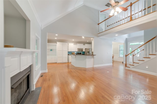 6414 Winding Creek Ln, Denver, NC 28037 - unfurnished living room featuring ornamental molding, stairs, a ceiling fan, a fireplace with flush hearth, and high vaulted ceiling