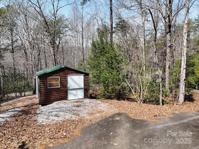 view of outdoor structure with an outbuilding and a view of trees