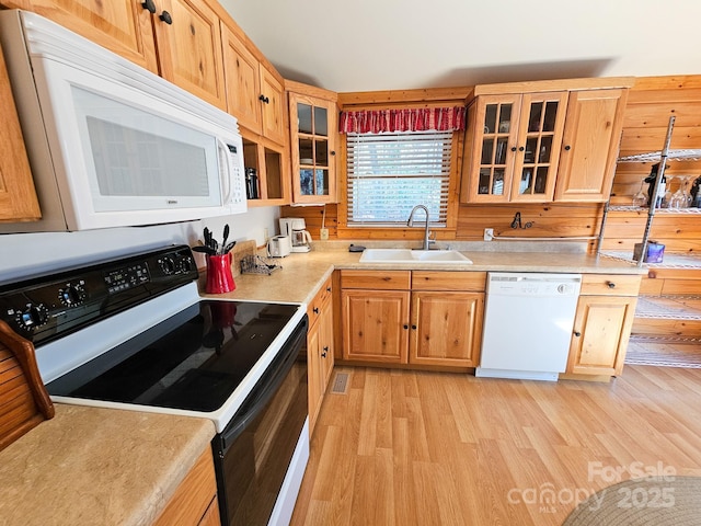kitchen with light countertops, a sink, glass insert cabinets, light wood-type flooring, and white appliances
