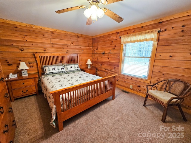 bedroom featuring a ceiling fan, carpet floors, wooden walls, and visible vents
