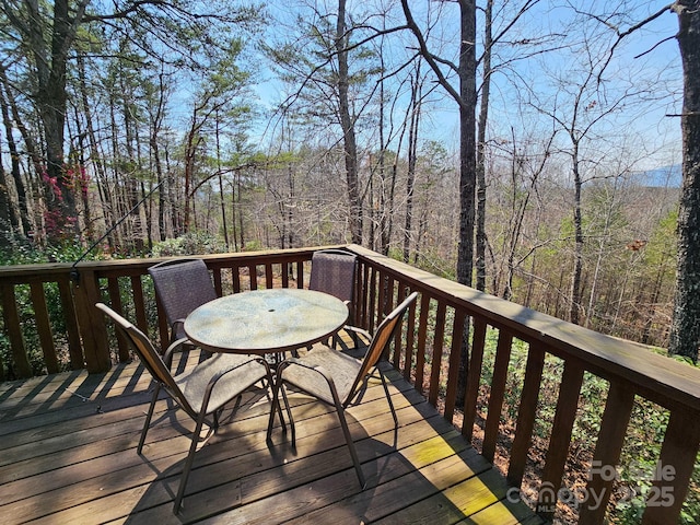 deck featuring outdoor dining space and a forest view