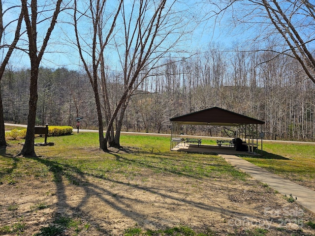 view of home's community with a gazebo, a wooded view, and a yard