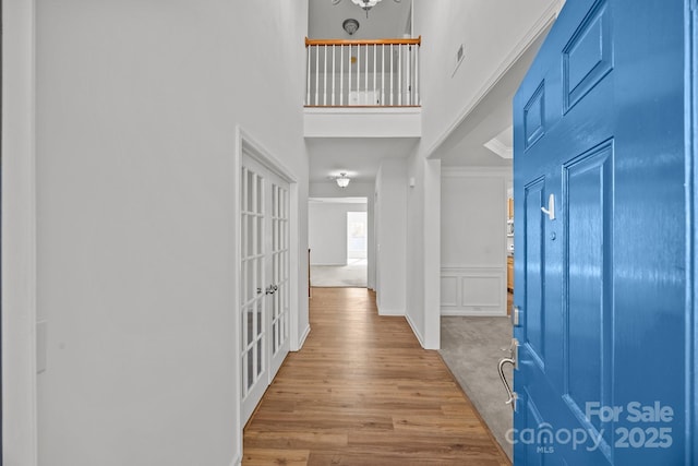 entryway with wainscoting, a high ceiling, wood finished floors, and a decorative wall