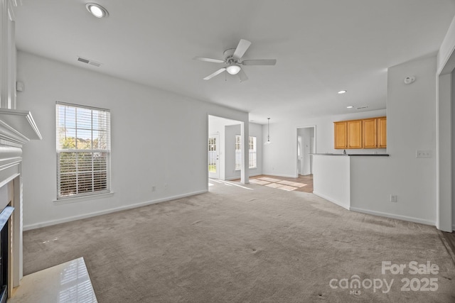 unfurnished living room featuring light colored carpet, recessed lighting, a fireplace with flush hearth, visible vents, and a ceiling fan