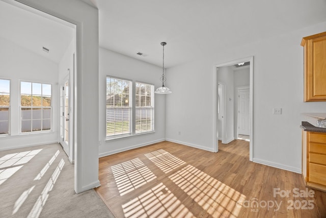 unfurnished dining area featuring baseboards, lofted ceiling, visible vents, and light wood finished floors