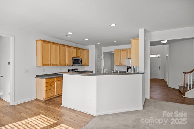 kitchen with dark countertops, stainless steel appliances, light wood-style floors, and recessed lighting