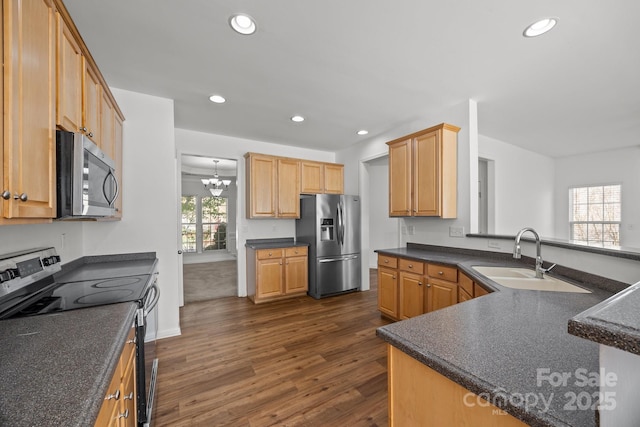 kitchen featuring dark wood-style flooring, a sink, dark countertops, and appliances with stainless steel finishes