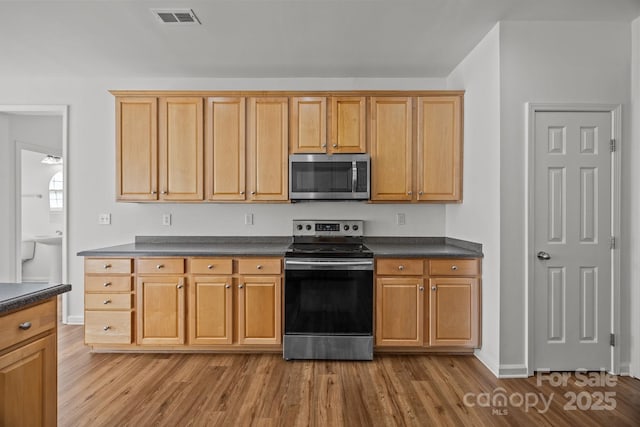 kitchen with visible vents, wood finished floors, dark countertops, and appliances with stainless steel finishes