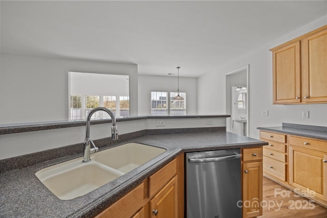 kitchen with decorative light fixtures, a sink, dark countertops, light wood-style floors, and dishwasher