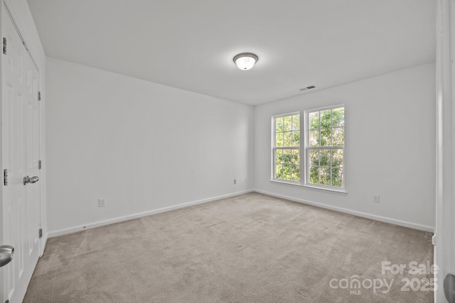 carpeted spare room featuring baseboards and visible vents