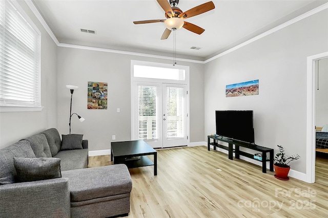 living room with visible vents, light wood-style floors, ornamental molding, and a ceiling fan