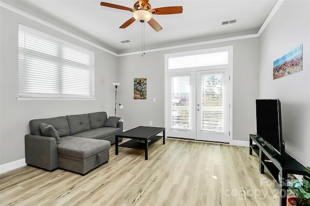 living room featuring ornamental molding, visible vents, ceiling fan, and light wood finished floors