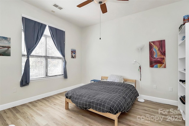 bedroom featuring visible vents, baseboards, ceiling fan, and wood finished floors
