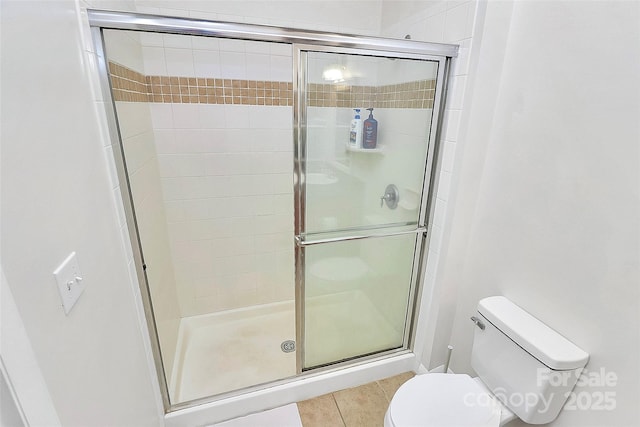 full bath featuring toilet, tile patterned floors, and a shower stall
