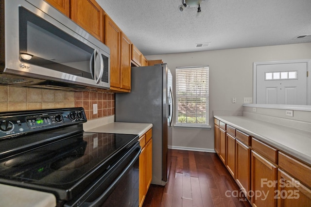 11929 Kings Castle Ct, Charlotte, NC 28277 - kitchen with black electric range oven, stainless steel microwave, decorative backsplash, visible vents, and brown cabinets