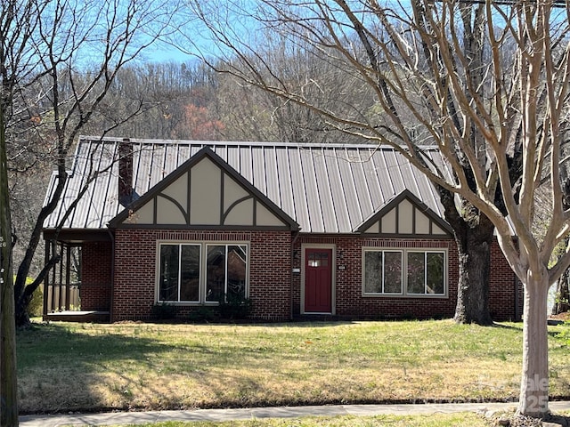 english style home featuring brick siding, a front lawn, and metal roof