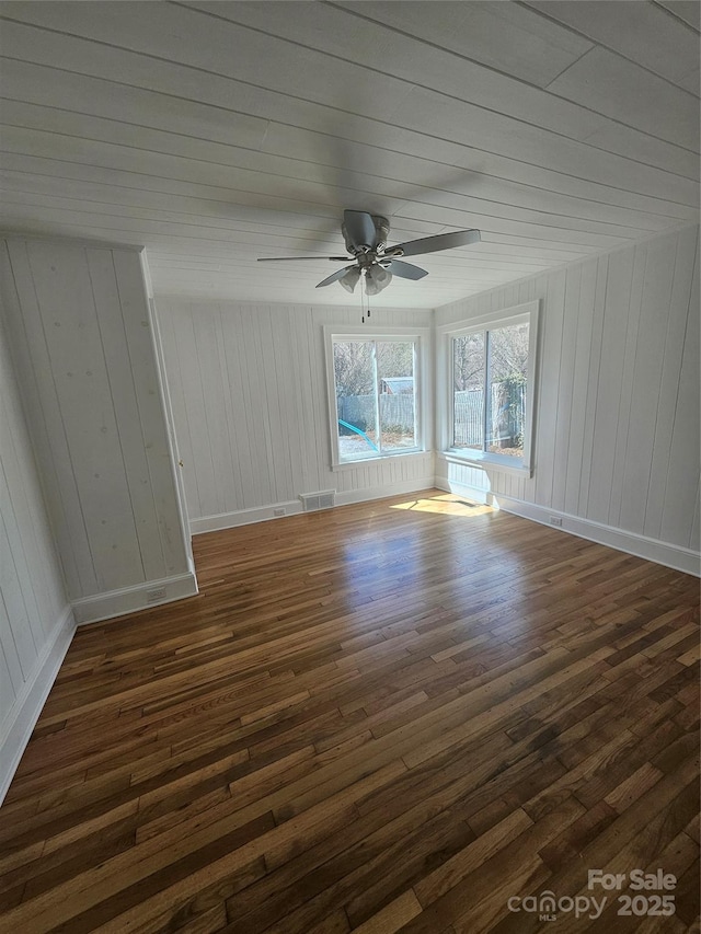 unfurnished room with a ceiling fan, dark wood-style flooring, baseboards, and visible vents