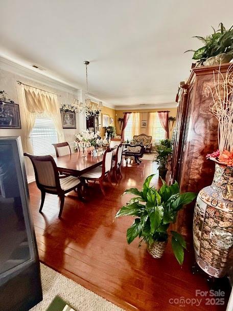 dining area with hardwood / wood-style floors, visible vents, and crown molding