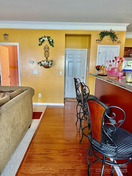 dining room featuring wood finished floors, crown molding, and baseboards