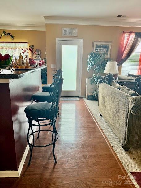 interior space featuring visible vents, baseboards, wood finished floors, and ornamental molding