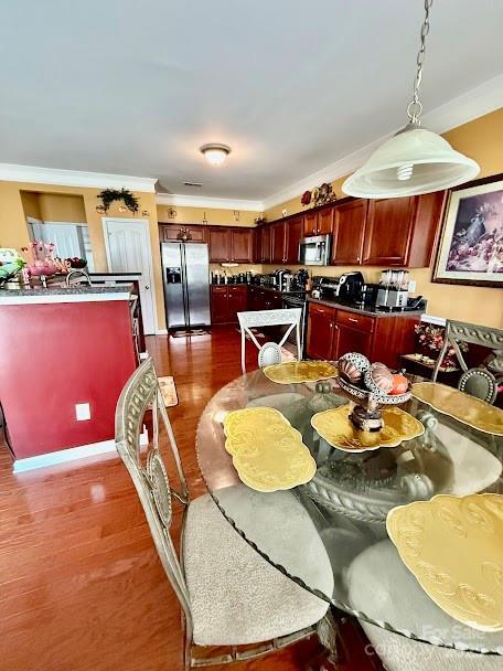 dining space featuring wood finished floors and ornamental molding