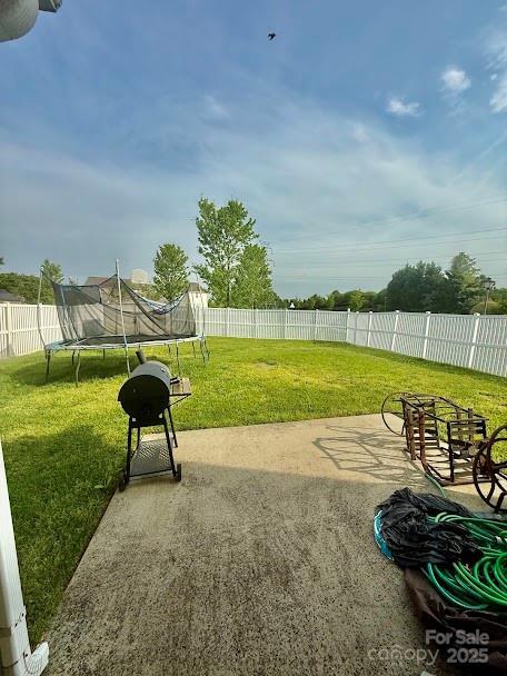 view of yard featuring a fenced backyard, a patio, and a trampoline