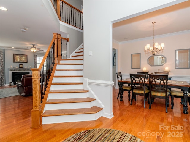 706 Springwood Dr Unit 14, Waxhaw, NC 28173 - staircase featuring ornamental molding, ceiling fan with notable chandelier, wood finished floors, and a fireplace