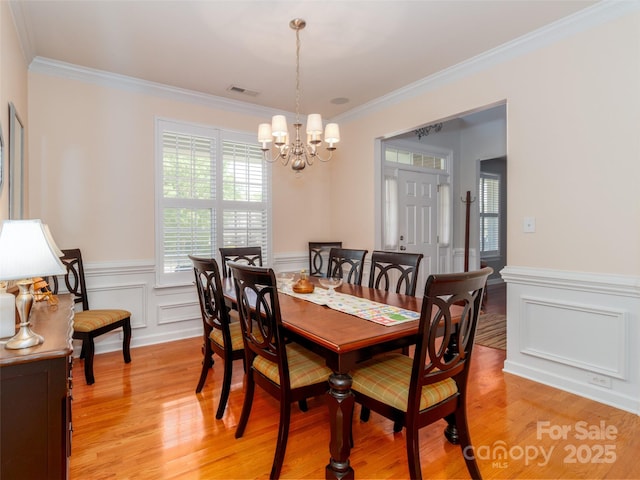 706 Springwood Dr Unit 14, Waxhaw, NC 28173 - dining room featuring visible vents, an inviting chandelier, crown molding, light wood finished floors, and a wainscoted wall