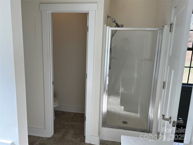 bathroom featuring baseboards, toilet, tile patterned floors, and a shower stall