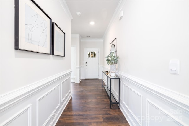 corridor featuring a decorative wall, dark wood-style flooring, ornamental molding, and a wainscoted wall