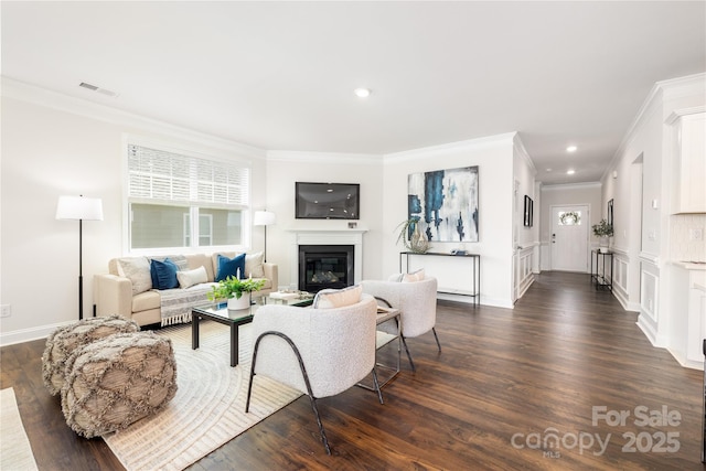 living area with visible vents, ornamental molding, dark wood-style floors, recessed lighting, and a glass covered fireplace