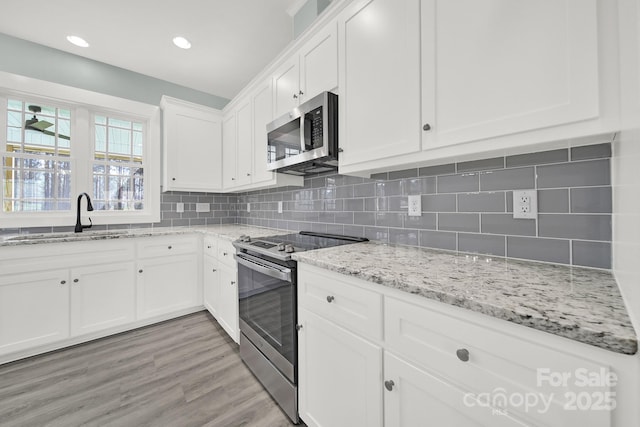 1380 Bowers Rd, Peachland, NC 28133 - kitchen with tasteful backsplash, stainless steel appliances, a sink, light wood finished floors, and white cabinets