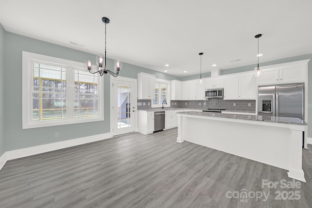 1380 Bowers Rd, Peachland, NC 28133 - kitchen with white cabinets, stainless steel appliances, tasteful backsplash, and wood finished floors