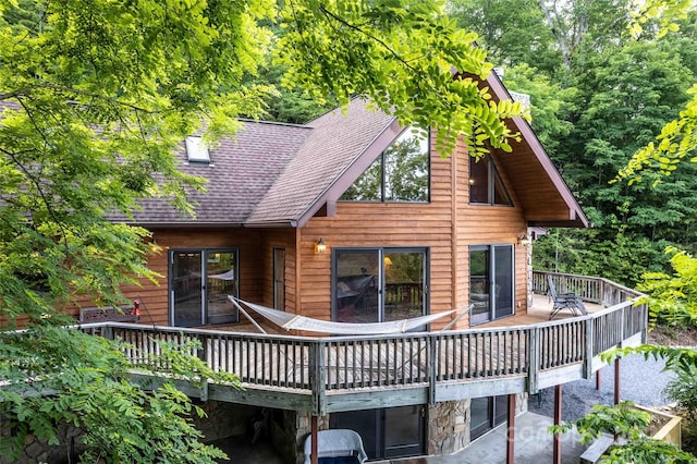 back of property featuring a shingled roof and a wooden deck