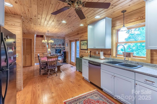kitchen with wood ceiling, stainless steel dishwasher, a sink, freestanding refrigerator, and ceiling fan with notable chandelier