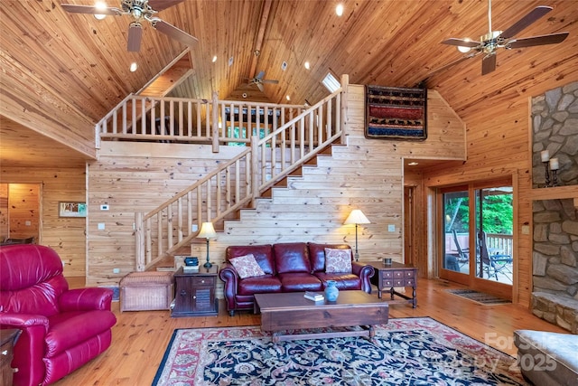 living room with wooden walls, a ceiling fan, high vaulted ceiling, and wooden ceiling