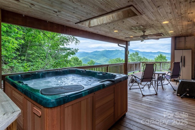deck featuring a ceiling fan, a mountain view, and a hot tub