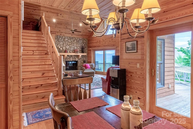 dining room with a notable chandelier, a fireplace, wood finished floors, wood ceiling, and stairway