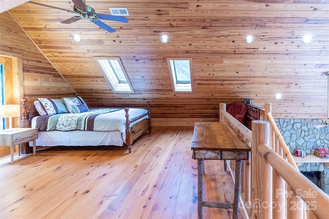 bedroom featuring visible vents, wooden walls, light wood-type flooring, vaulted ceiling with skylight, and wooden ceiling