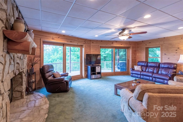 carpeted living room featuring plenty of natural light, wood walls, ceiling fan, and a paneled ceiling