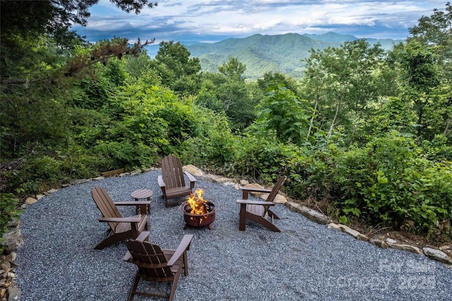 view of patio featuring a view of trees, a mountain view, and an outdoor fire pit