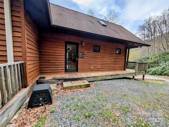 rear view of house featuring roof with shingles and a deck