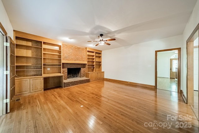 5232 Silchester Ln, Charlotte, NC 28215 - unfurnished living room with a ceiling fan, light wood-type flooring, built in shelves, baseboards, and a brick fireplace