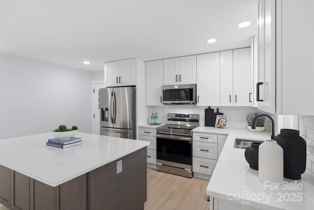 1315 Vickie Ln, Matthews, NC 28104 - kitchen with stainless steel appliances, light countertops, tasteful backsplash, light wood finished floors, and white cabinets